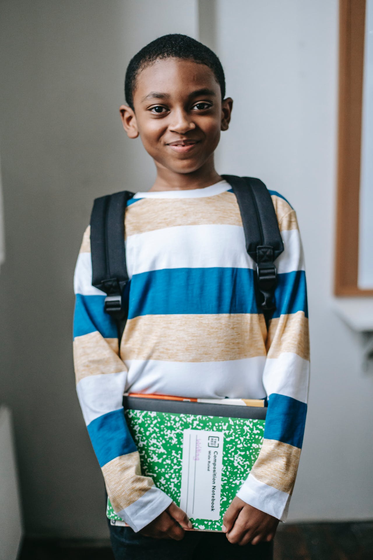 Student with backpack holding a composition notebook